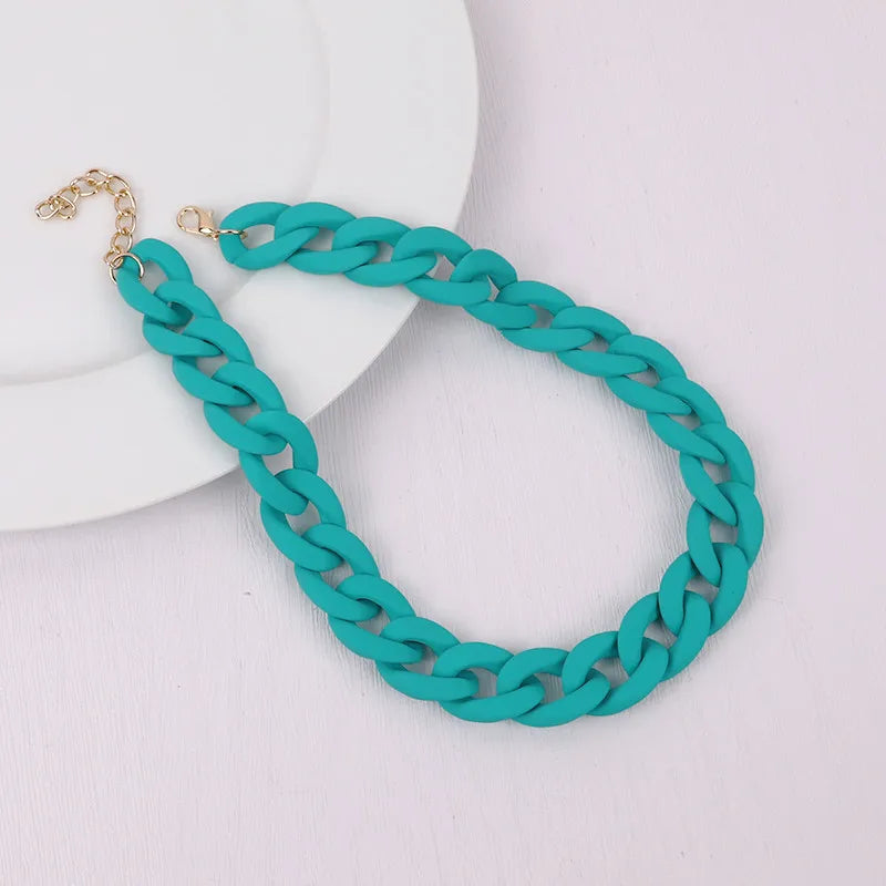 A turquoise acrylic chain necklace with a gold clasp laid on a white plate.