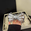 Silver heart-shaped acrylic evening clutch with a delicate chain strap being held in a hand.