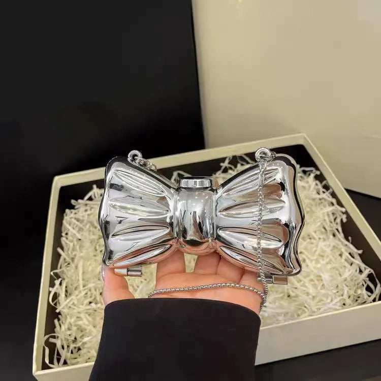 Silver heart-shaped acrylic evening clutch with a delicate chain strap being held in a hand.