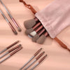 Una colección de 13 brochas de maquillaje profesionales, incluidas brochas para sombras y base, exhibidas sobre un paño rosa 