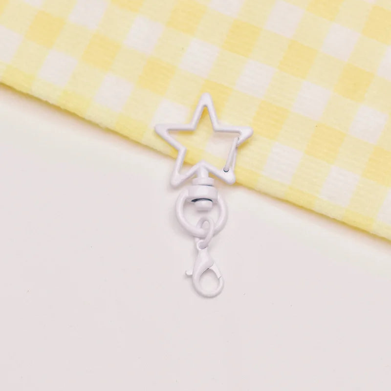 A silver star-shaped metal keychain clasp set resting on a yellow and white checkered fabric.