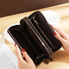 A dark brown vintage PU leather zippered wallet with multiple compartments is held by a hand on a light wooden surface.