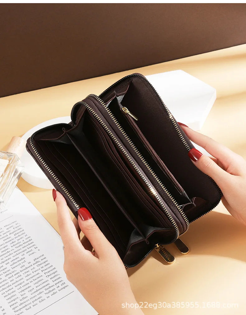 A dark brown vintage PU leather zippered wallet with multiple compartments is held by a hand on a light wooden surface.