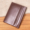 A dark brown genuine leather bifold card holder resting on a wooden surface.