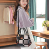 Une femme modélise un sac bandoulière en cuir PU noir et blanc avec une chemise violet clair à l'intérieur.