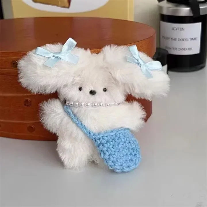 A fluffy white rabbit charm with light blue bows and a matching blue knitted pouch.