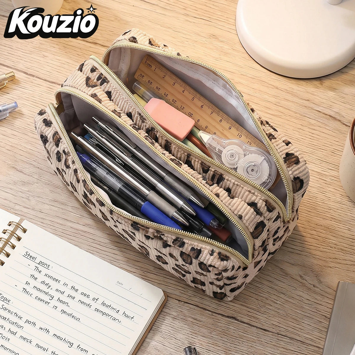 حقيبة قلم ذات سحّاب مزدوج بنقشة نمر مليئة بالأقلام على طاولة خشبية.