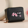 Black faux leather zipper wallet with gold accents and a pink floral butterfly print