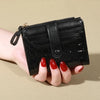 A hand holds a black PU leather card wallet with a double zip closure.