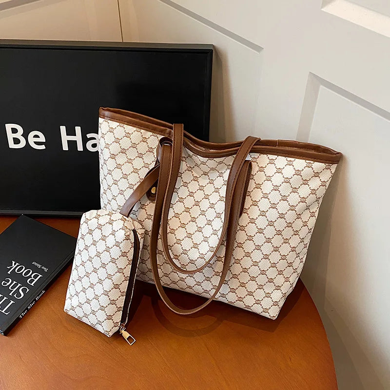 A beige and white geometric patterned tote bag with brown leather trim resting on a wooden surface.