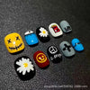 A collection of colorful, bean-shaped press-on nails featuring various designs including cartoon faces and symbols.
