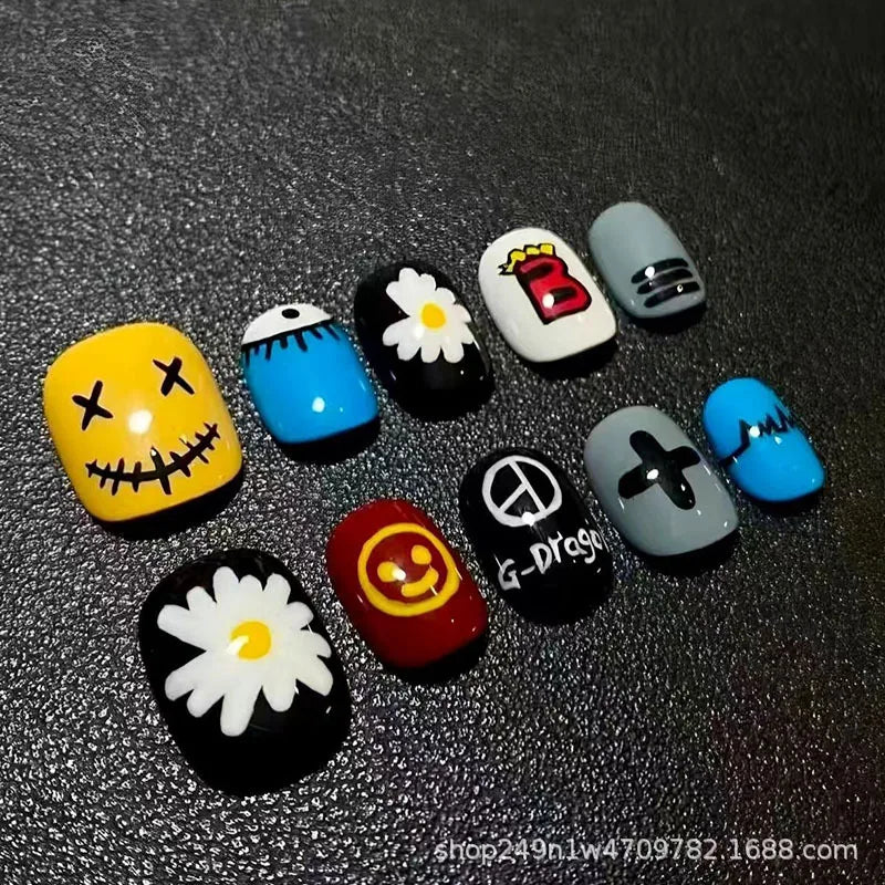 A collection of colorful, bean-shaped press-on nails featuring various designs including cartoon faces and symbols.