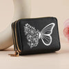 Black leather zipper wallet with a white butterfly floral print resting on a light surface.