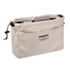 A beige drawstring canvas storage organizer bag filled with various small items like a phone and cosmetic containers.
