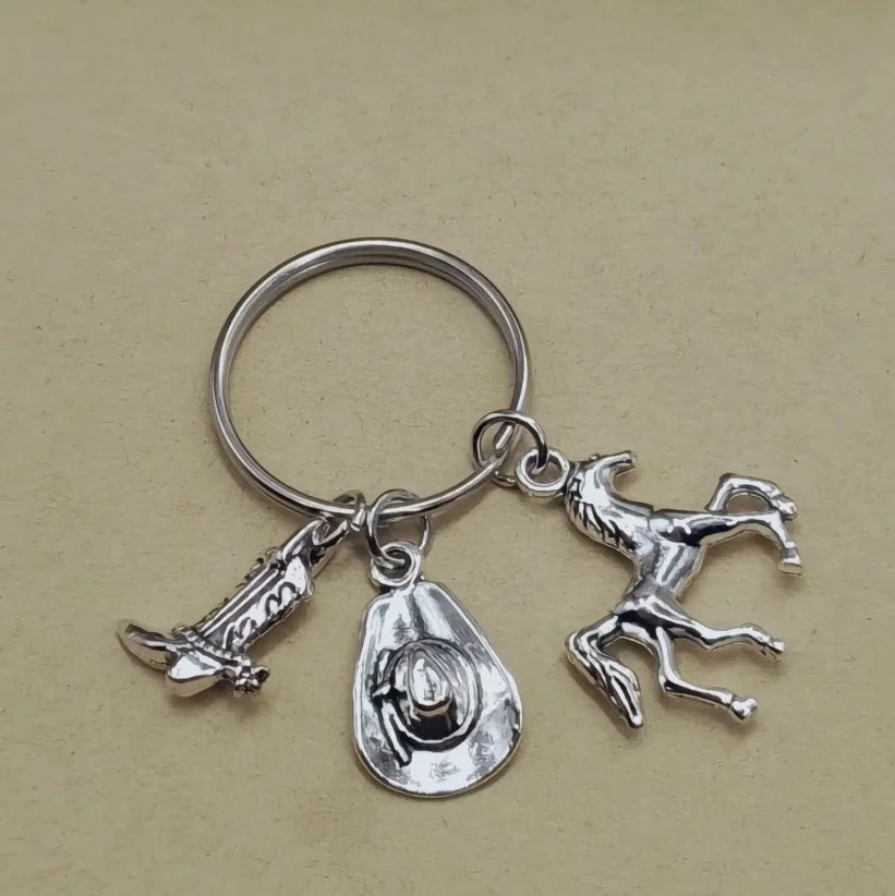 Silver keychain set featuring a cowboy boot, hat, and horseshoe charms.