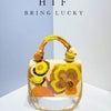 A handcrafted clutch bag featuring embroidered floral patterns in yellow, orange, and gold threads.