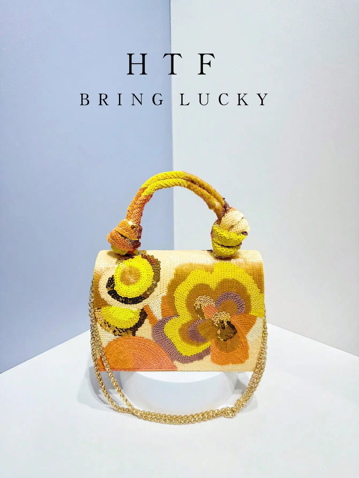 A handcrafted clutch bag featuring embroidered floral patterns in yellow, orange, and gold threads.