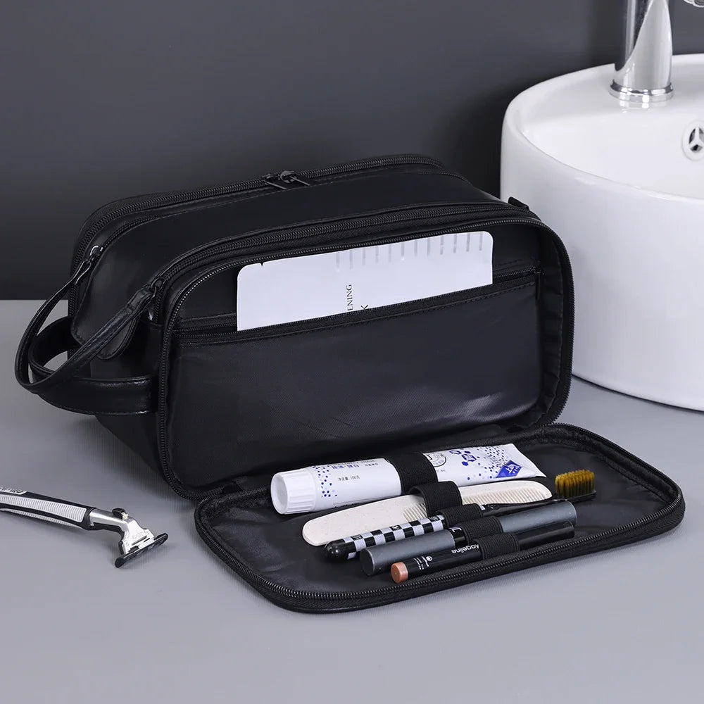 A black PU leather travel toiletry bag with organizer pockets and a brush is shown on a gray surface.