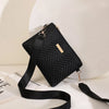 A black quilted chain crossbody bag with gold hardware resting on a white surface.