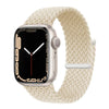 A silver Apple Watch is shown with a beige braided stretch band around it.