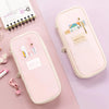 A pink pencil case with a zipper, featuring a special tag and various stationery items, displayed on a light purple surface.