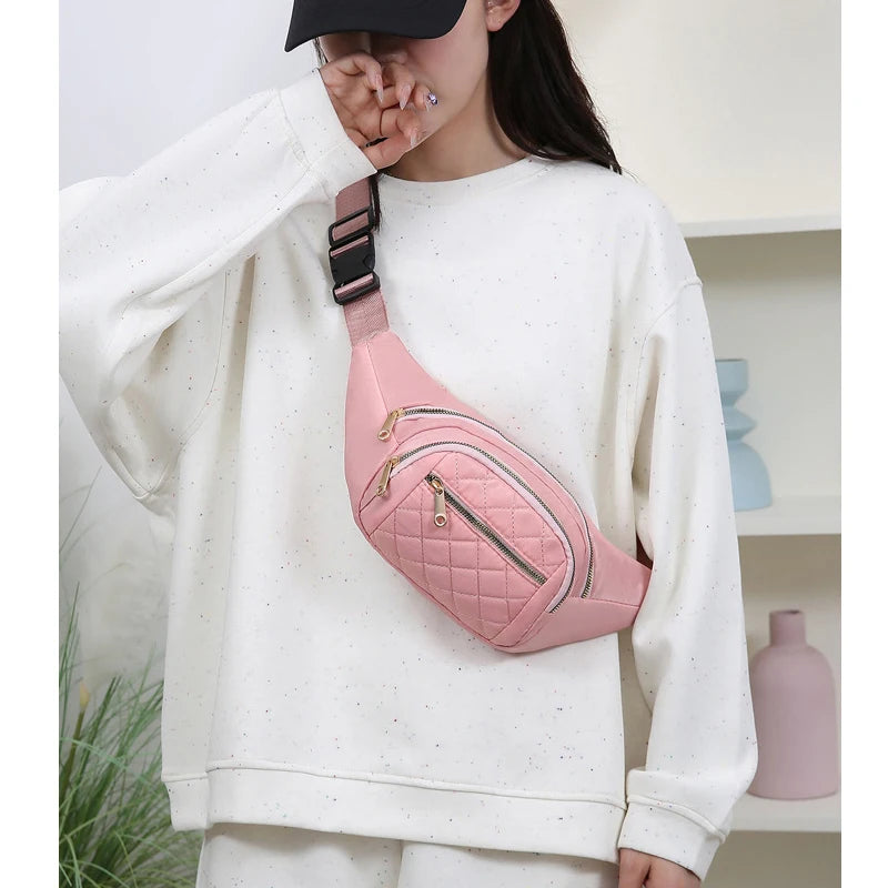 A person wearing a white sweatshirt is holding a pink quilted nylon crossbody belt bag.