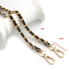 Gold and black metal chain shoulder strap with adjustable clasps shown next to a white cylindrical object.