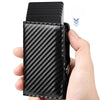 A hand holds a black slim RFID-blocking card holder with a carbon fiber texture.