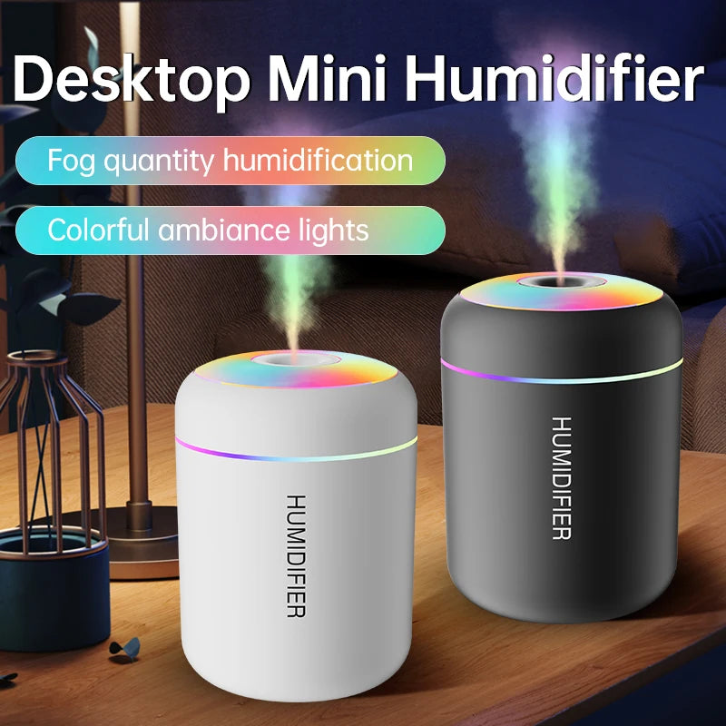 A white desktop mini humidifier with colorful ambient lights is shown on a wooden surface.