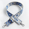 A blue and white floral jacquard strap for a crossbody bag, featuring a silver buckle.