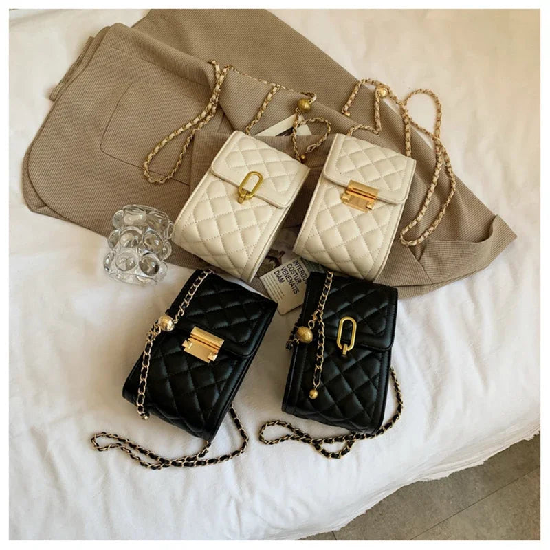 A collection of quilted leather crossbody bags in cream and black with gold metal straps resting on a beige fabric.