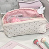 A pink and white polka dot shell pencil case with a zippered interior and a matching pink cosmetic pouch.