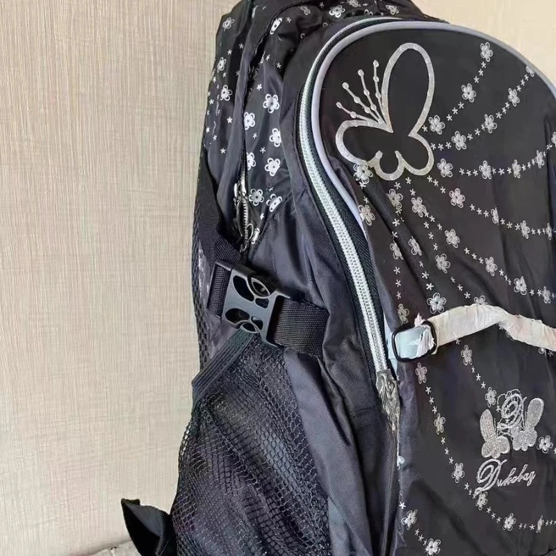 A black backpack featuring a butterfly print design and mesh panel.