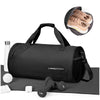 A black waterproof travel duffel bag with a shoe compartment and accessories displayed on a gray mat.