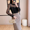 A woman models a glitter pleated crossbody clutch bag with a detachable chain against a light background.
