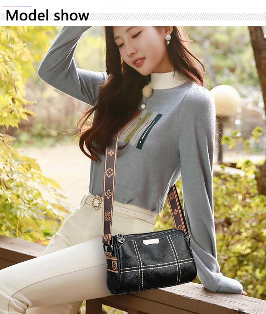 A woman models a black luxury cowhide shoulder bag while wearing a gray turtleneck sweater and white pants outdoors.