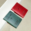 A red leather passport holder and a dark green leather passport wallet are displayed on a light background.