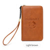 A light brown leather passport holder with a lanyard and an embossed world design.