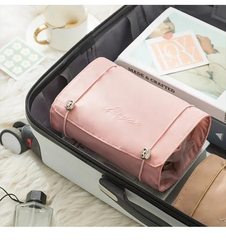 A pink portable makeup bag with a leather trim is shown inside an open travel case.