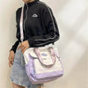 Eine Person hält eine lila-weiße Nylon-Tasche und einen schwarzen Hoodie.