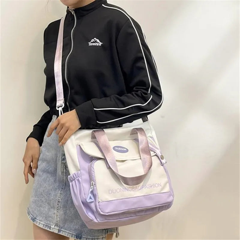 Eine Person hält eine lila-weiße Nylon-Tasche und einen schwarzen Hoodie.