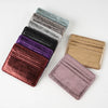 A stack of slim leather mini wallet card holders in various shades including black, purple, and gold.