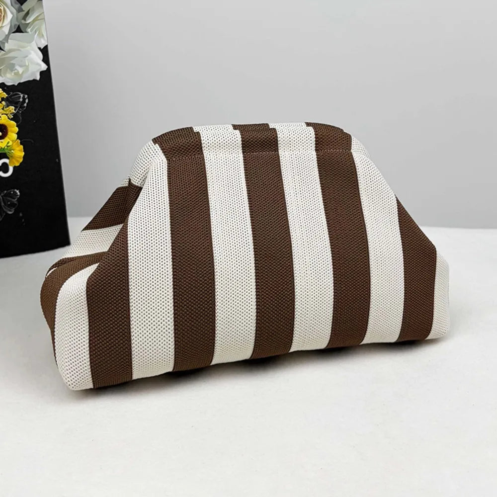 A beige and brown striped knit cloud makeup bag lying on a white surface.