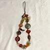 A necklace made of various colored beads with a black cord and a small charm.