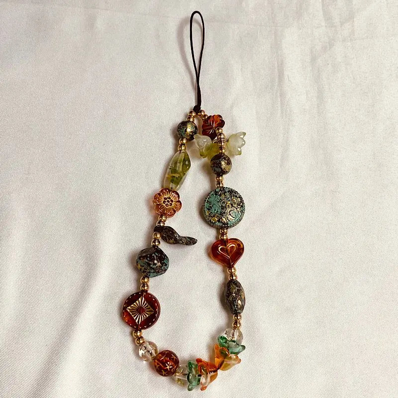 A necklace made of various colored beads with a black cord and a small charm.
