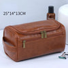 A brown leather toiletry bag with a zipper and brass hardware is shown next to a bottle.