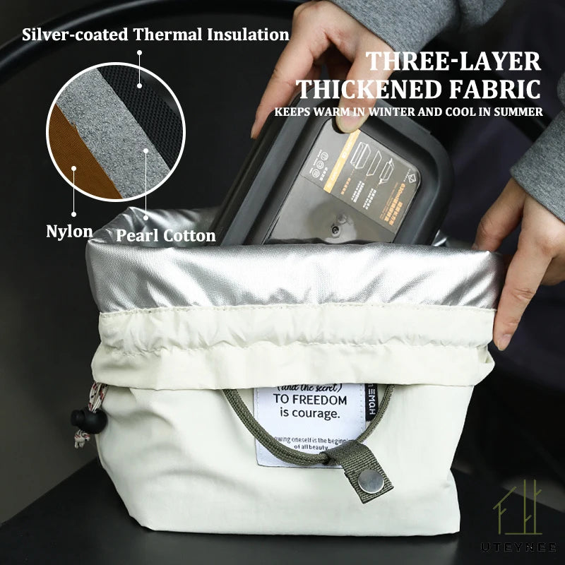 A hand is holding a silver-coated thermal insulation bag with a three-layer thickened fabric and a drawstring closure.