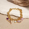 A gold chain bracelet featuring ocean pearl charms including a purple star and translucent shell accents.