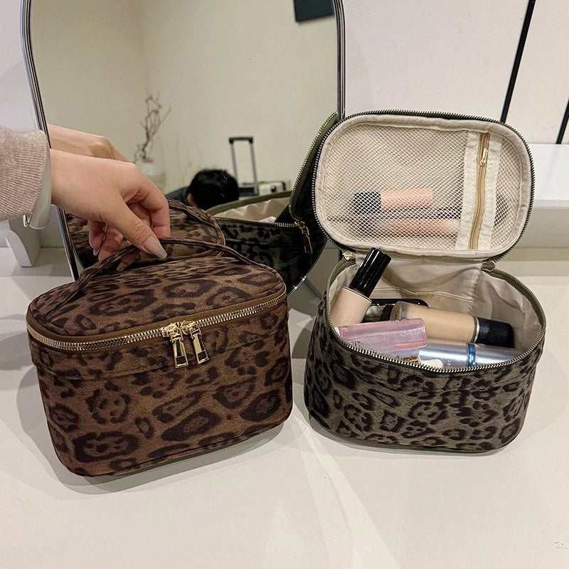 A brown faux suede cosmetic bag with a gold zipper is shown open, revealing makeup products.