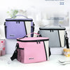 Three insulated reusable lunch bags in purple, pink, and gray are displayed on a white surface.